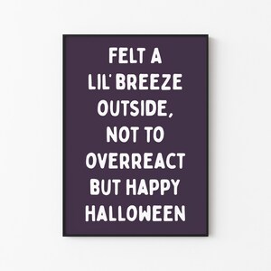 Pode incluir: Uma impressão emoldurada com fundo roxo escuro e texto branco. O texto diz "FELT A LIL' BREEZE OUTSIDE, NOT TO OVERREACT BUT HAPPY HALLOWEEN." A impressão é uma decoração com tema de Halloween.