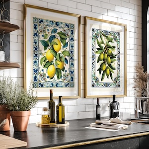 Op de afbeelding: Twee ingelijste rechthoekige wandkunstprints met botanische illustraties. De linkerprint toont gele citroenen aan takken, terwijl de rechterprint groene olijven aan takken weergeeft. Beide prints zijn omrand door blauw-witte tegelpatronen.