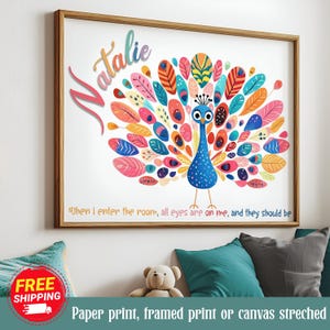 以下が含まれることがあります： カラフルな孔雀のイラストが描かれたフレームプリント。孔雀は青い体と、ピンク、オレンジ、黄色、青色の羽を持つ鮮やかな尾を持っています。「Natalie」という名前が孔雀の上に書かれています。