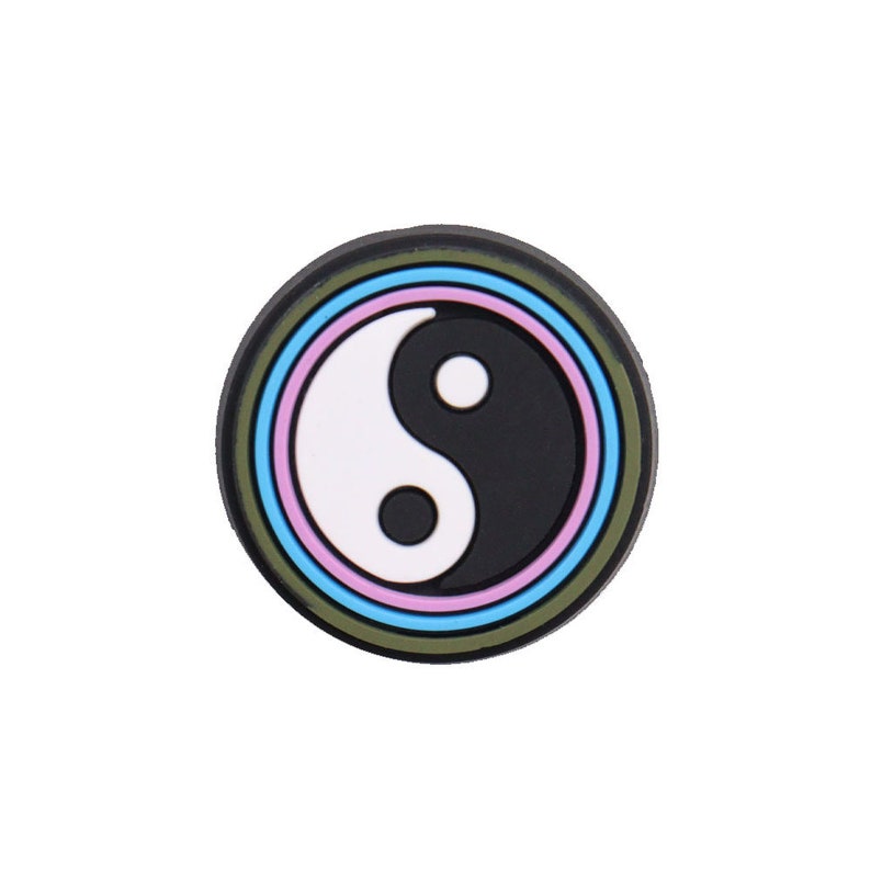 Pu&ograve; includere: Un simbolo yin yang bianco e nero con un anello blu, rosa e verde intorno.