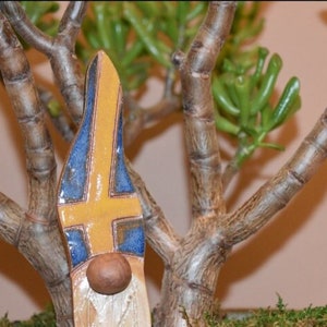 May include: A ceramic gnome figurine with a yellow, blue and white hat. The hat is painted with the colours of the Swedish flag.