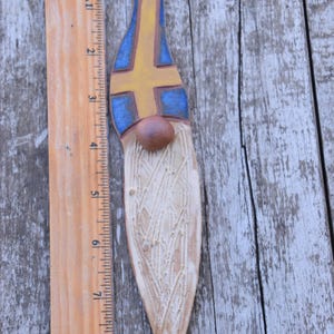 May include: A ceramic gnome figurine with a white beard and a blue and yellow hat. The hat is painted with the colors of the Swedish flag. The gnome is approximately 8 inches tall.