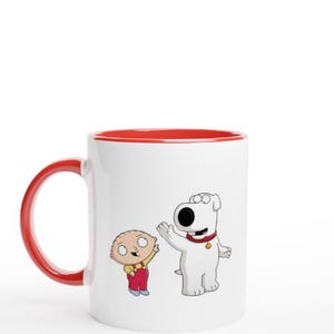 May include: A white ceramic mug with a red rim features a cartoon illustration of Brian Griffin, the dog from Family Guy, and Stewie Griffin, the baby from Family Guy. Brian is standing on his hind legs with his mouth open, and Stewie is standing on his feet with his arms raised.