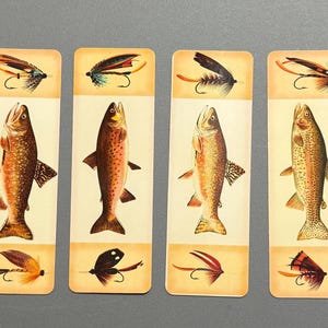 May include: Four rectangular bookmarks with illustrations of fish and fishing flies. Each bookmark features a different fish species and a corresponding fly pattern. The fish are depicted in detail with realistic coloring and scales. The background is a cream color.