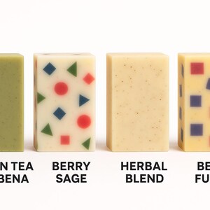 Peut inclure: Quatre savons rectangulaires de couleurs et motifs vari&eacute;s. Le premier est vert, &eacute;tiquet&eacute; "Green Tea Verbena". Le second est blanc avec des formes color&eacute;es, &eacute;tiquet&eacute; "Berry Sage". Le troisi&egrave;me est beige, &eacute;tiquet&eacute; "Herbal Blend". Le quatri&egrave;me est jaune avec des carr&eacute;s, &eacute;tiquet&eacute; "Berry Fusion".
