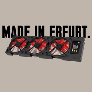 May include: Three black computer fans with red and white blades, mounted on a black panel with a digital display showing the temperature. The panel has the text "MADE IN ERFURT."