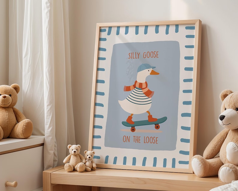 May include: A framed art print depicting a cartoon goose skateboarding. The goose is wearing a blue cap, striped shirt, and scarf. The print has a light blue background with the words "SILLY GOOSE ON THE LOOSE". The frame is light wood.