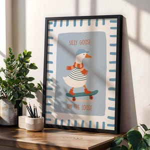 May include: Framed art print with a cartoon goose on a skateboard. The goose is wearing a blue cap, striped shirt, and scarf. Text reads "SILLY GOOSE ON THE LOOSE". The frame is black, and the background is light blue.