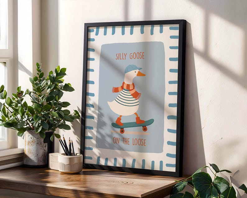 May include: Framed art print with a cartoon goose on a skateboard. The goose is wearing a blue cap, striped shirt, and scarf. Text reads "SILLY GOOSE ON THE LOOSE". The frame is black, and the background is light blue.