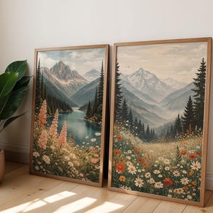 May include: Two framed landscape art prints. One features a river scene with mountains and pink flowers. The other depicts a meadow with wildflowers and mountains. Both are in wooden frames, creating a cohesive set.