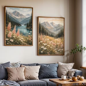 May include: Two framed landscape paintings depict mountain scenes with a lake and wildflowers. The artwork features a palette of blues, greens, and pinks, with a wooden frame. The paintings are displayed above a gray sofa with pillows.