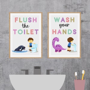 May include: Two framed illustrations with colorful text. The left illustration shows a boy flushing a toilet with a whale swimming in the water below. The right illustration shows a boy washing his hands with a dinosaur standing next to him. The text on the left reads "FLUSH the TOILET" and the text on the right reads "WASH your HANDS".