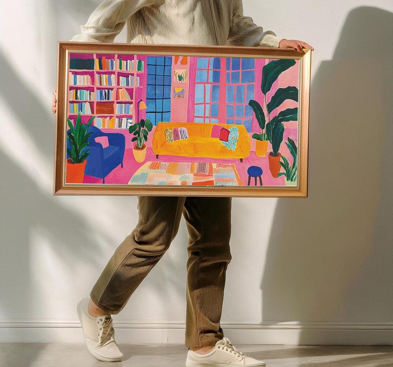 Puede incluir: Una ilustraci&oacute;n enmarcada de una sala de estar con una pared rosa, un sof&aacute; amarillo, un sill&oacute;n azul, una estanter&iacute;a y una planta en maceta. La ilustraci&oacute;n est&aacute; en un marco dorado.