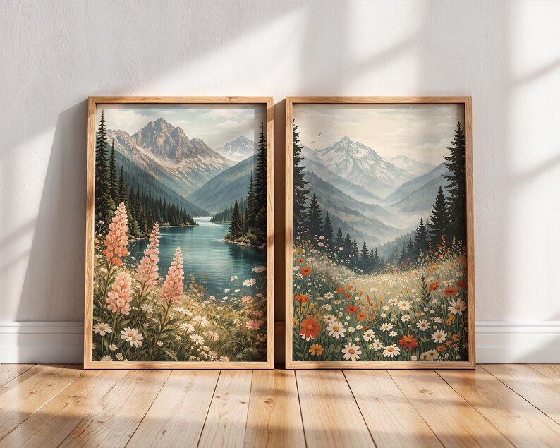 May include: Two framed landscape art prints. One features a mountain lake scene with pink flowers, the other a meadow with wildflowers. Both have wooden frames and depict mountains, trees, and water in a watercolor style.