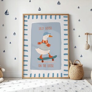 May include: A framed art print depicting a goose on a skateboard. The goose is dressed in a striped top, scarf, and cap. The text reads "SILLY GOOSE ON THE LOOSE". The background is light blue with a white border.