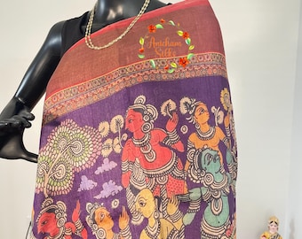 May include: Purple silk saree with a hand-painted design featuring a scene of people and trees. The saree has a red border and the text "Anicham Silks" is embroidered in the upper right corner.