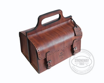 May include: A brown leather tool bag with a top handle and two buckles. The bag has a label that says "Strongway Tools" and "Handmade - Forge of Ukraine".