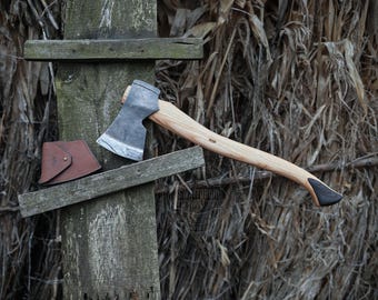 May include: A hand-forged axe with a wooden handle and a leather sheath. The axe head is made of steel and has a sharp edge. The handle is made of wood and has a natural finish. The sheath is made of leather and has a brown color.