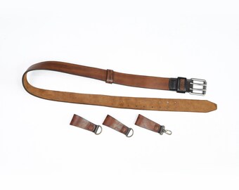 May include: A brown leather belt with a silver buckle and three leather loops with metal rings.