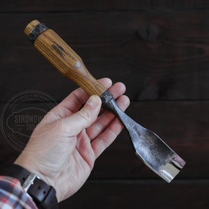 Könnte beinhalten: Ein Holzmeißel mit einem schwarzen Metallblatt. Der Griff ist mit "Strongway Tools" gekennzeichnet.