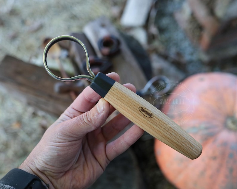 May include: A wood-handled loop tool with a black ferrule and a metal loop. The tool has the brand name "Swaydogue Tools" printed on the wooden handle. The tool is designed for shaping clay or other materials.