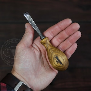 Puede incluir: Una pequeña herramienta de talla de madera hecha a mano con un mango de madera. El mango está grabado con las palabras "Strongway Tools".