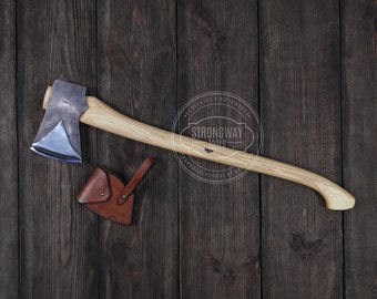May include: A wood-handled axe with a blue steel head and a leather sheath. The axe is on a dark wood background. The text "Strongway Tools" is on a circular label.