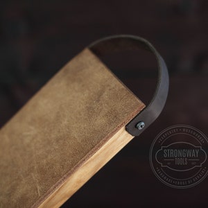 May include: A brown leather-wrapped wooden tray with a black leather handle. The tray has a distressed look and is made by Strongway Tools.