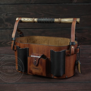 May include: A brown leather tool bag with multiple pockets and a wooden handle. The bag has a black leather trim and a brass buckle. The bag is labeled "Strongway Tools".