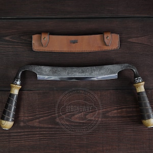 May include: A curved, hand-forged woodworking tool with wooden handles and a leather sheath. The tool is made by Strongway Tools.