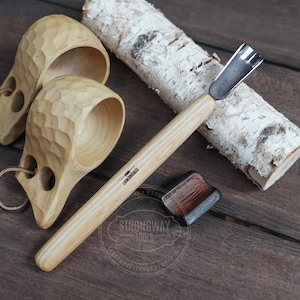 以下が含まれることがあります： 革の取っ手が付いた木製のカップが2つと、金属製の刃が付いた木製の彫刻工具。工具には「Strongway Tools」のラベルが貼られています。