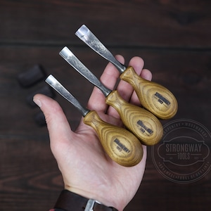 以下が含まれることがあります： 木製のハンドルが付いた木彫りの道具が3つあります。道具は金属製の刃が付いており、「Strongway Tools」とラベル付けされています。