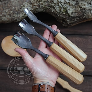 May include: Three wood carving tools with wooden handles. The tools are made of metal and have a curved blade. The handles are made of light brown wood with a grain pattern. The tools are held in a person's hand.