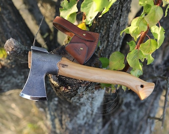 May include: A small, hand-forged axe with a wooden handle and a leather sheath. The axe is made by Strongway Tools, a company that supports the people of Ukraine.