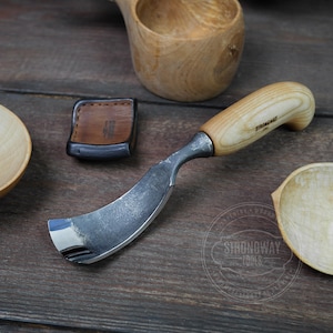 May include: A wood carving tool with a curved blade and a wooden handle. The handle is made of light wood with a dark wood grain. The blade is made of metal and has a sharp edge. The tool is on a wooden surface.