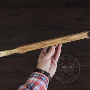 May include: A wooden plane with a light wood handle and a metal clamp. The plane is held in a hand. The text "Strongway Tools" is visible in the image.
