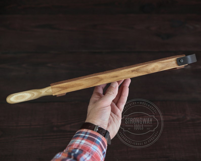 May include: A wooden plane with a light wood handle and a metal clamp. The plane is held in a hand. The text "Strongway Tools" is visible in the image.