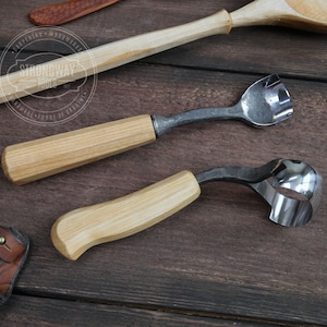 May include: Two wood carving tools with wooden handles. The tools are made of metal and have a curved blade. The tools are on a wooden surface. The tools are labeled "Strongway Tools".