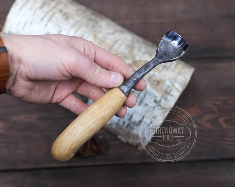 May include: A wooden handled carving tool with a curved metal blade. The tool is made by Strongway Tools, Handmade Forge of Ukraine.