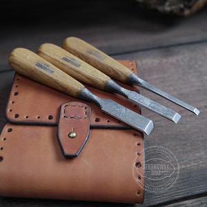 Peut inclure: Ensemble de quatre ciseaux à bois avec manches en bois, dans un étui en cuir marron avec le logo Strongway Tools.