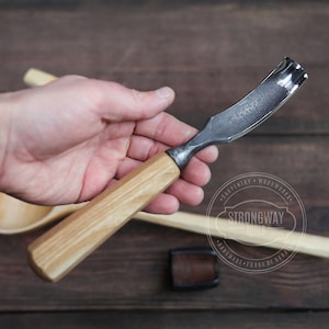 Puede incluir: Una herramienta de talla de madera con una cuchilla curva y un mango de madera. La herramienta está hecha por Strongway Tools, una empresa especializada en herramientas hechas a mano.