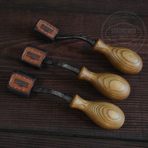 May include: Three wood-handled carving tools with black metal blades. Each tool has a leather label with the text "Strongway Tools" on it.