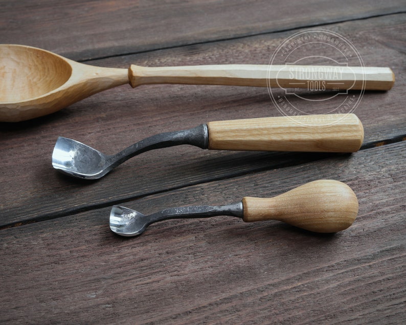 Pu&ograve; includere: Tre strumenti di intaglio con manico in legno e lame in metallo. Gli strumenti sono disposti su una superficie in legno. Lo strumento pi&ugrave; grande &egrave; un cucchiaio di legno. I due strumenti pi&ugrave; piccoli sono strumenti di intaglio a forma di cucchiaio. Gli strumenti sono etichettati "Strongway Tools".