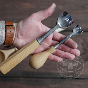 May include: Two wooden handled carving tools with metal blades. The tools have a unique design with multiple teeth on the blade. The tools are held in a hand with a tattoo.