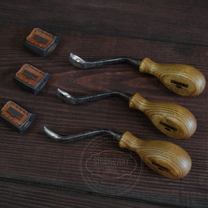 May include: Three wood carving tools with brown wooden handles and black metal blades. The handles are engraved with the text "Strongway Tools".