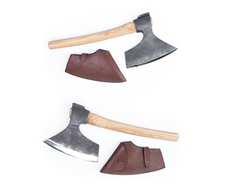 May include: Two hand-forged axes with wooden handles and leather sheaths. The axes have a curved blade and a rounded head. The sheaths are brown leather and have a flap that secures with a snap.