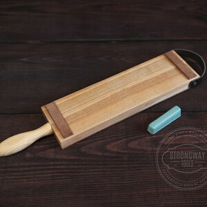 May include: A wooden strop with a leather strap and a light blue honing stone. The strop is used for sharpening straight razors.