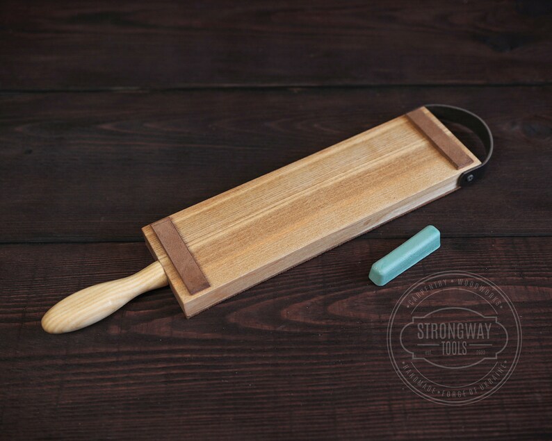 May include: A wooden strop with a leather strap and a light blue honing stone. The strop is used for sharpening straight razors.