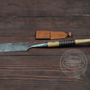 May include: A wooden-handled chisel with a metal blade and a leather sheath. The chisel is on a wooden surface with a logo that says "Strongway Tools - Carpentry - Woodwork - Handmade - Forge of Ukraine".