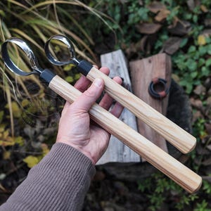Puede incluir: Dos gubias para tallar madera con hojas de acero pulido y mangos de madera clara. Las gubias tienen un collar negro donde la hoja se encuentra con el mango. El texto "SWAYTOBOR TOOLS" es visible en la hoja. Las herramientas se sostienen en una mano.